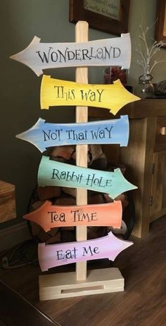 a wooden sign that has different colored arrows on it and the words wonderland, this way, not that way, rabbit hole, tea time, eat me