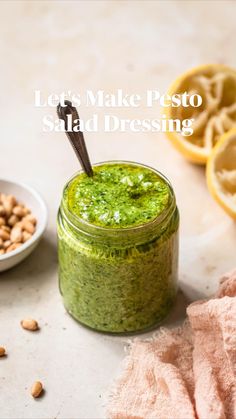 a jar filled with pesto next to two lemons and nuts