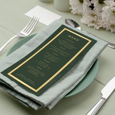 a menu on a plate with silverware and white flowers in the backgroud