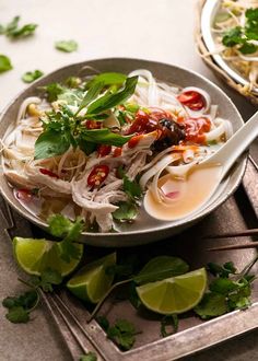 a bowl filled with noodles and garnishes on top of a table