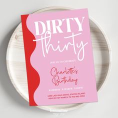 a pink and red birthday party card sitting on top of a white plate with the words dirty thirty printed on it