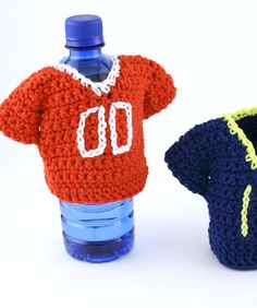 two crocheted sweaters and a water bottle cover are sitting next to each other