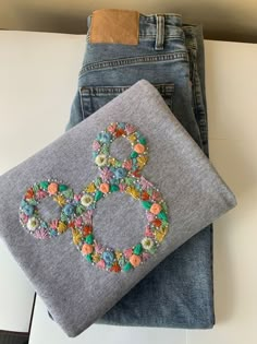 a pair of jeans with an embroidered peace sign on one side and flowers on the other