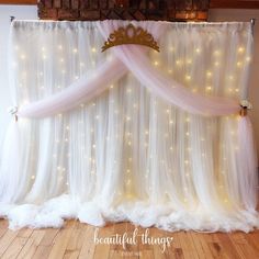 a white curtain with lights on it and a tiara hanging from the top, in front of a brick wall