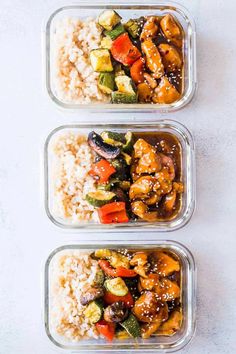 three plastic containers filled with rice and veggies on top of a white table