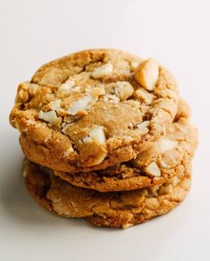 three cookies stacked on top of each other with white chocolate chunks in the middle and one cookie topped with sea salt