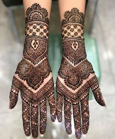 two hands with henna tattoos on them, one is showing the intricate pattern and the other has an ornate design