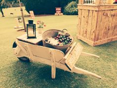 a wheelbarrow filled with beer bottles in the grass next to a wooden crate