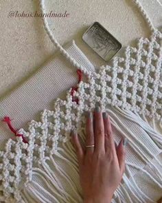 a woman's hand is on the edge of a piece of crochet