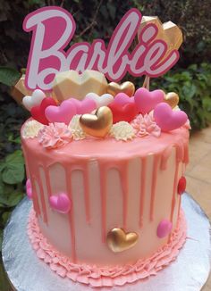 a pink and gold cake with the word barbie on top