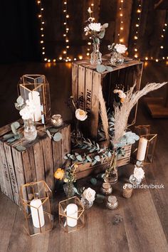 an arrangement of candles, flowers and other decorations on a wooden crate with lights in the background