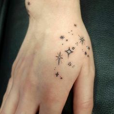 a woman's hand with stars and moon tattoos on it