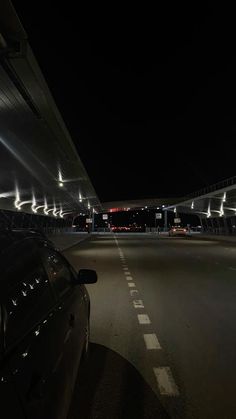 an empty parking lot at night with cars parked on the side and lights shining from above