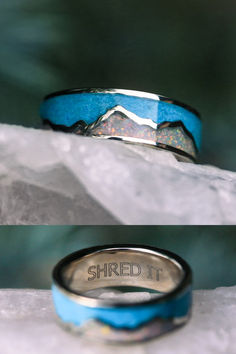 A "Peak" wedding band from Staghead Designs sits on an icy surface. This 14K white gold band features a mountain design with crushed opal inlay as the mountains & crushed turquoise as the sky. This ring also features a custom engraving on the inside of the band that reads "SHRED IT". Turquoise White Opal Ring Men, Opal Wedding Ring Boy, Mountain Wedding Band, Whiskey Barrel Wedding Ring, Antler Wedding Rings, Ring Engraving, Handcrafted Engagement Ring, Wood Wedding Ring, White Gold Wedding Band