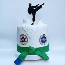 a cake with a karate figure on top and green ribbon around the edge that is tied to it