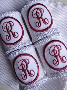 three white and red towels with monogrammed letters on them, sitting on top of each other