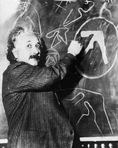 a man writing on a blackboard with the word r = o written in chalk