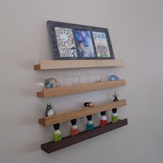 three wooden shelves with bottles on each shelf and two pictures hanging above the top one