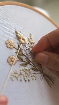 someone is stitching flowers on a piece of fabric with a needle in their hand