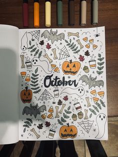 an open coloring book with halloween decorations and bats on it, surrounded by crayons