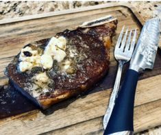 a piece of steak on a cutting board next to a fork