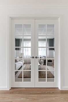 two white double doors with mirrors on them in a room that has hardwood floors and walls