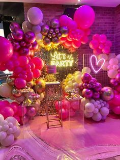 balloons and streamers are on display in a room decorated with pink, yellow, and purple colors