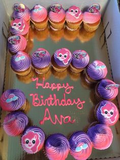 a box filled with lots of cupcakes covered in pink and purple frosting