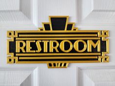 a black and gold sign that says restroom on the side of a white door,