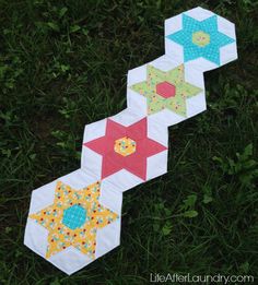 three quilted hexagons laying on the grass