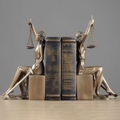 a statue of lady justice sitting next to two books