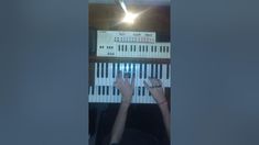 a person is playing the keyboard in front of an electronic device with their hands on it