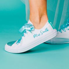 a close up of a person's feet wearing white sneakers with blue bows on them