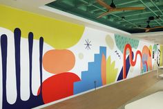 an office with colorful murals on the wall and ceiling fan hanging from the rafters