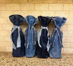 three denim bags with ties tied to them sitting on a counter next to a brick wall