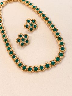 Beautiful and rare Trifari Necklace and Earring Set that looks like fine jewelry.  The necklace is crafted of round faceted emerald rhinestones set in a golden beaded bezel and surrounded by another delicate ring of gold.   The earrings feature a 6 round faceted emerald s with the unique Trifari clip.  Trifari is known for excellence in design and quality. This set is in perfect condition. Hand Set Round Emerald Necklace, Round Emerald Necklace Hand Set, Elegant Round Beads Emerald Necklace For Festive Occasions, Formal Green Jeweled Jewelry Sets, Gold Emerald Jewelry Sets For Party, Gold Emerald Jewelry Sets For Formal Occasions, Gold Emerald Jewelry Sets For Formal Events, Green Temple Jewelry Sets For Formal Occasions, Matte Gold Necklace