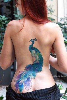 the back of a woman's body with a peacock tattoo on her lower back