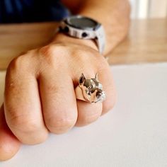 a person wearing a ring with a dog on it's middle finger, sitting at a table