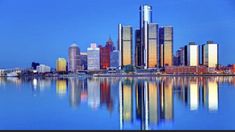 a city skyline is reflected in the water at night time with blue sky and clouds