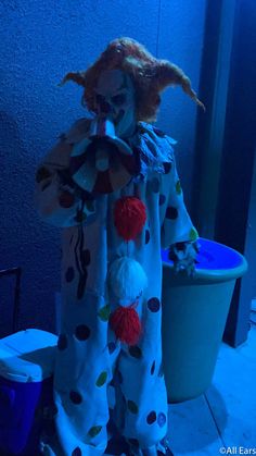 a creepy clown doll standing next to a trash can