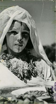 an old black and white photo of a woman with beads on her face