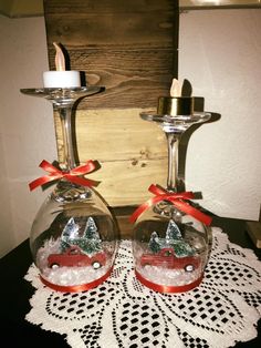 two clear glass candlesticks with red cars in them on a lace doily