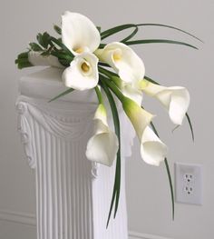 a white vase with flowers in it sitting on a table next to a light switch