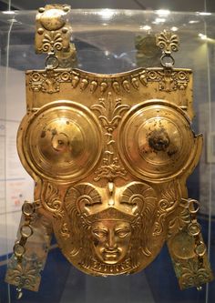 a gold mask is in a glass case