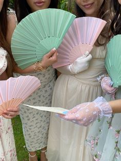 four women in dresses holding pink and green fans