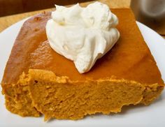 a piece of pumpkin pie with whipped cream on top is sitting on a white plate