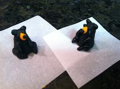 two small black bears sitting on top of paper