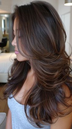 Woman with voluminous, layered brown hair standing in a room. Lowlights On Red Hair, Inverted Lob, Balayage Asian Hair