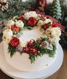 a white frosted cake with red and white flowers on it sitting on a table