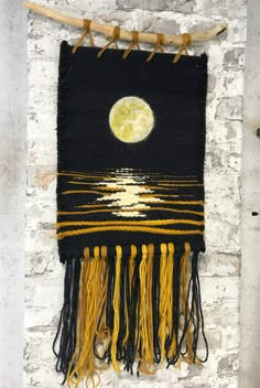 a black and yellow wall hanging on a brick wall with a full moon in the background